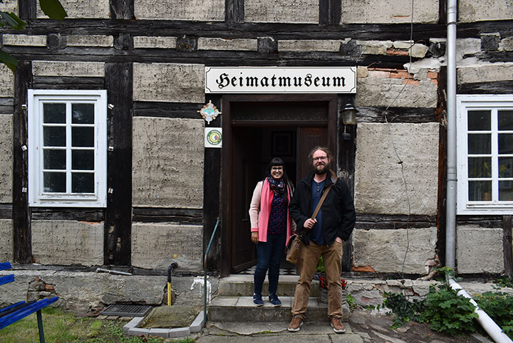 Eine Frau und ein Mann stehen vor dem Eingang eines Fachwerkhauses.